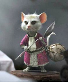 a small rat dressed in red and white holding a large metal ball with two hands