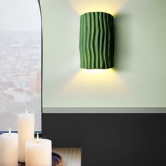 three candles sitting on top of a table next to a wall mounted candle holder and window