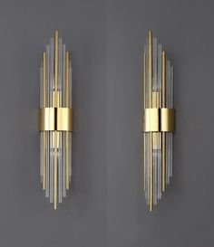 two wall sconces with gold and clear glass rods on the sides, one in front of the other