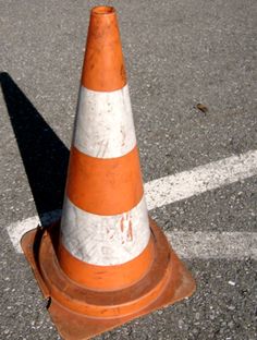 an orange and white cone sitting on top of a parking lot