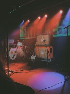 the band is performing on stage with their instruments in front of bright colored spotlights