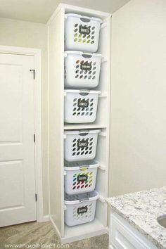 a white shelf filled with plastic baskets next to a marble counter top and door in the background