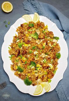 a white plate topped with rice covered in broccoli and lemon wedges next to a fork