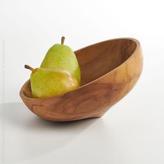 two pears in a wooden bowl on a white surface