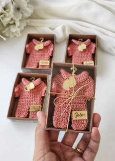 a person is holding three small baby sweaters in their boxes with tags on them