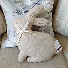 a stuffed rabbit sitting on top of a couch next to pillows