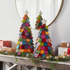 two christmas trees made out of felt sitting on top of a table next to presents