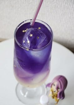 a purple drink sitting on top of a white table next to a small figurine