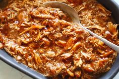 a casserole dish with shredded meat and a wooden spoon in it, ready to be eaten