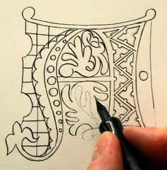 someone is drawing an ornamental design on paper with a black marker and pen, while the image appears to be in full color