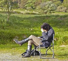 a woman sitting in a chair talking on her cell phone while looking at the ground