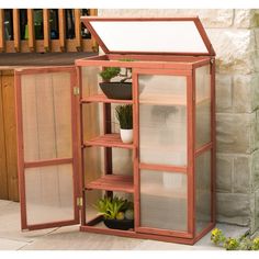 a potted plant inside of a small wooden cabinet next to a brick wall and stairs