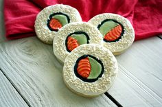 four decorated cookies sitting on top of a white wooden table next to a red towel