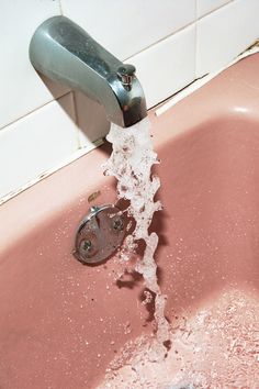 a faucet running out of a pink sink with water coming from the faucet