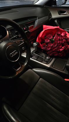 a bouquet of roses sits in the center console of a car, next to a steering wheel