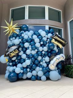 a large balloon arch with balloons and confetti on it in front of a building