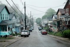 cars are parked on the street in front of houses and power lines that run through them