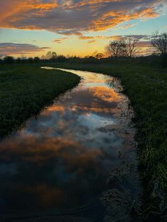 the sun is setting over a small stream