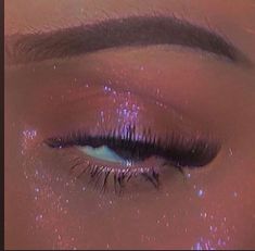 a woman's eye with pink glitter on it