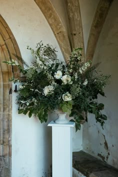 a vase filled with flowers sitting on top of a white pedestal