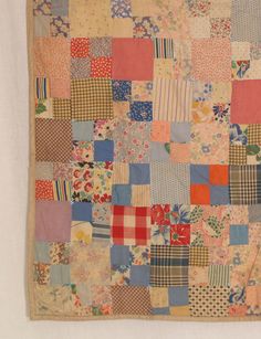 an old patchwork quilt hanging on a wall