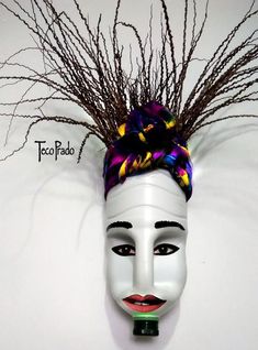 a white mask with purple and yellow flowers on it's head is displayed against a white wall