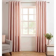 pink curtains hanging in front of a window with white walls and wooden flooring next to a gray chair