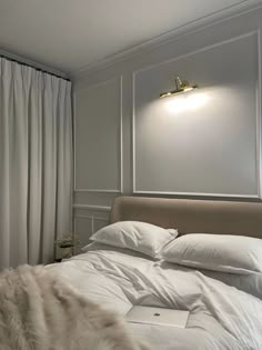 a bed with white sheets and pillows next to a window in a room that has curtains on the windowsill