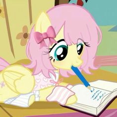 a pinkie sitting at a desk with a book and pen in her mouth,