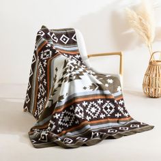 a blanket sitting on top of a wooden chair next to a vase filled with flowers