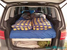 the back end of a van with pillows and blankets in it's cargo area