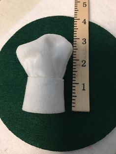 a white piece of cloth sitting next to a ruler on top of a green circle