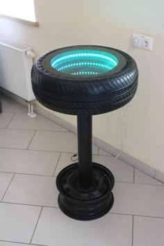 an illuminated tire on top of a black pedestal in a room with tile flooring