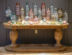 a wooden table topped with lots of glass bottles