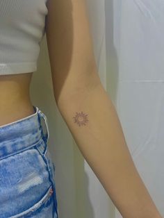 a woman with a small sun tattoo on her arm