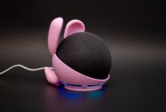 a pink and black speaker sitting on top of a table next to a white cord