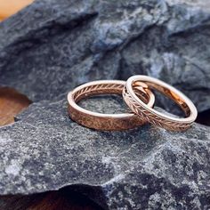 two wedding rings sitting on top of a rock