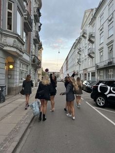 three women are walking down the street taking pictures