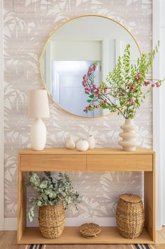 a mirror and some plants on a shelf in front of a wallpapered wall