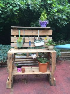 a wooden bench with potted plants and gardening utensils hanging from the back