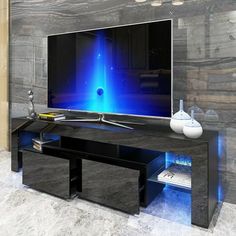 a large flat screen tv sitting on top of a black entertainment center next to a white vase