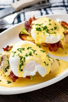 two eggs benedicts with bacon and cheese on a white plate