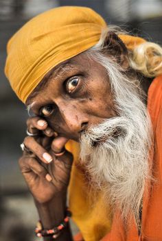 an old man with a yellow turban and white beard is looking at the camera