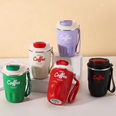 four coffee mugs sitting next to each other on a white counter top with the lids off