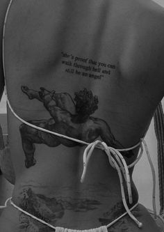 the back of a woman with tattoos on her body and an inscription written on it