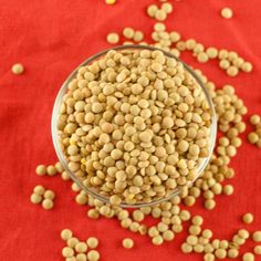 a glass bowl filled with peas on top of a red cloth