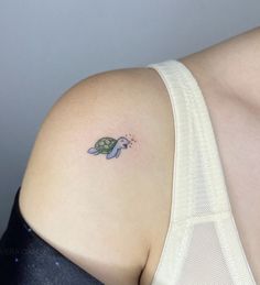 a small turtle tattoo on the back of a woman's left shoulder and arm