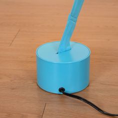 a toothbrush holder on the floor with a cord attached to it and a blue cover