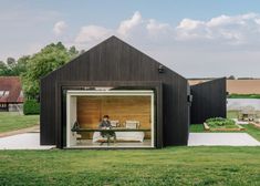 a person sitting at a table in the back of a black building with open doors