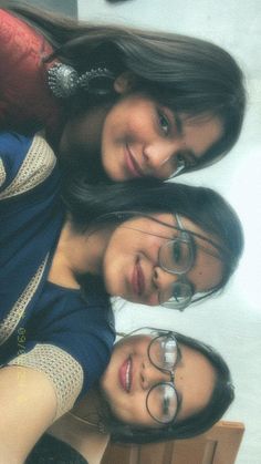 three young women are posing for the camera with their arms around each other and wearing eyeglasses